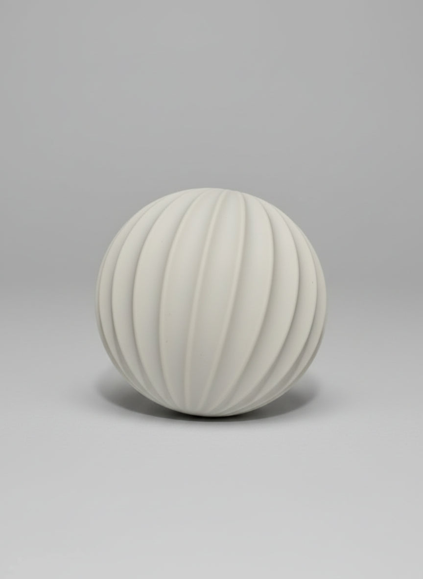 Minimalist 1.5kg weighted Pilates ball (side view) in oat latte silicone for toning and deep muscle engagement